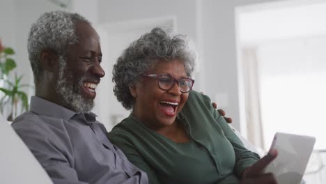 Ein-älteres-Afroamerikanisches-Paar,-Das-Zu-Hause-Lacht.-Soziale-Distanzierung-In-Quarantäne
