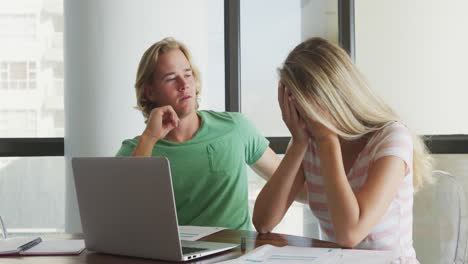 Caucasian-stressed-couple-at-home-using-a-laptop-during-coronavirus-covid19-pandemic
