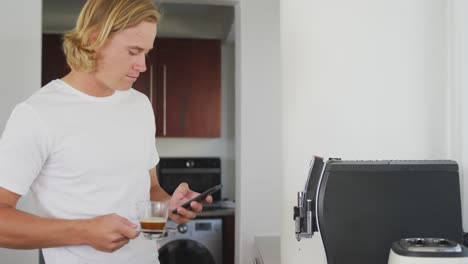 Mann-Hält-Kaffeetasse-In-Der-Hand,-Während-Er-Sein-Smartphone-Benutzt