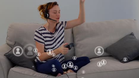 Animation-of-people-icons-flying-over-a-woman-playing-a-video-game-at-home