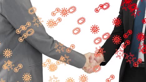 Covid-19-icons-over-two-businessman-shaking-hands-against-white-background