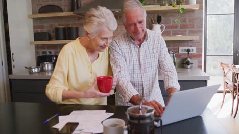 Senior-Caucasian-couple-happily-working-together-on-a-laptop-at-home
