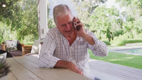 Senior-Caucasian-man-smiling-and-talking-on-the-phone-in-the-garden