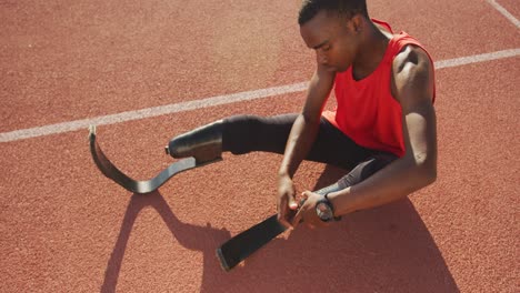 Disabled-mixed-race-man-with-prosthetic-legs-sitting-on-racing-track