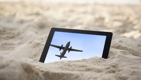 Animation-Eines-Digitalen-Tablets-Im-Sand-Mit-Einem-Fliegenden-Flugzeug-Auf-Dem-Bildschirm