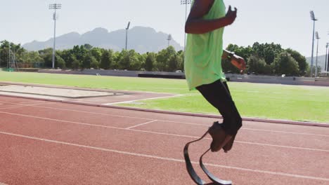 Disabled-mixed-race-man-with-prosthetic-legs-running-on-race-track-and-stopping