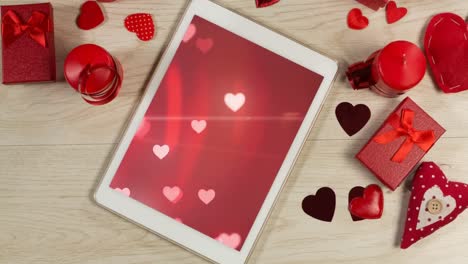 Animation-of-a-digital-tablet-with-multiple-heart-floating-on-red-background-on-the-screen-