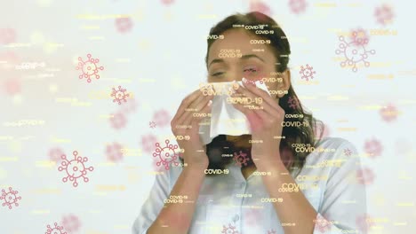 Animation-of-words-Covid-19-and-macro-Covid-19-cells-icons-floating-over-Asian-woman-sneezing-into-a
