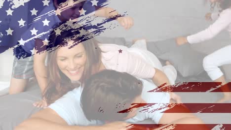 Animation-of-U.S.-flag-drawing,-red-and-blue-stars-floating-over-Caucasian-family-playing-in-bed