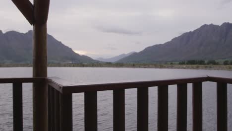 A-view-of-a-lake-and-mountains-during-sunset-on-a-cloudy-day-seen-from-log-cabin-window