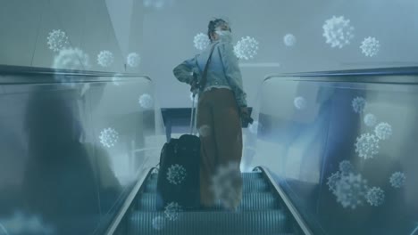 Animation-of-macro-Covid-19-cells-floating-over-Asian-woman-wearing-a-face-mask-and-using-escalator