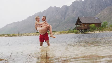 Caucasian-couple-having-a-good-time-on-a-trip-to-the-mountains,-wearing-bathing-suits-and-standing-i