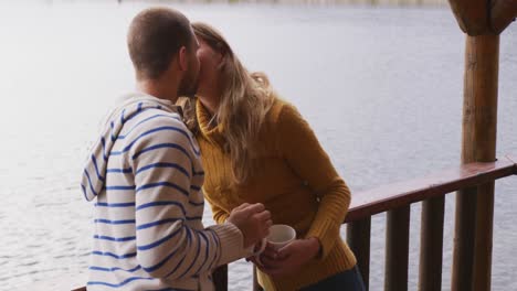 Caucasian-couple-spending-time-at-home-together,-kissing-outside-the-cabin