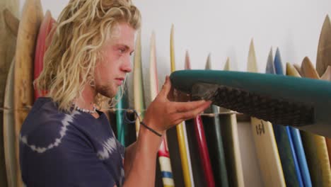 Caucasian-male-surfboard-maker-checking-one-of-the-surfboards-in-his-studio