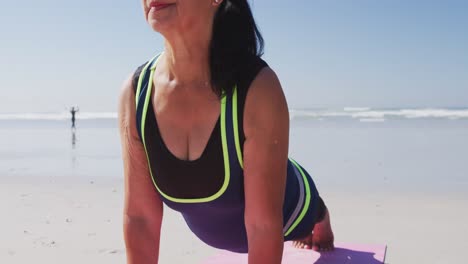 Kaukasische-Frau-Macht-Yoga-Position-Am-Strand-Und-Blauer-Himmel-Im-Hintergrund
