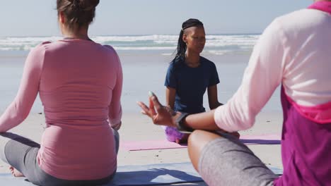 Multiethnische-Gruppe-Von-Frauen,-Die-Yoga-Am-Strand-Und-Vor-Blauem-Himmel-Machen