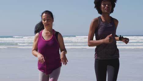 Grupo-Multiétnico-De-Mujeres-Corriendo-En-La-Playa-Y-El-Fondo-Del-Cielo-Azul