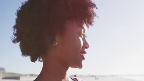 Mujer-Afroamericana-Mirando-La-Vista-Y-Sonriendo-En-La-Playa-Y-El-Fondo-Del-Cielo-Azul
