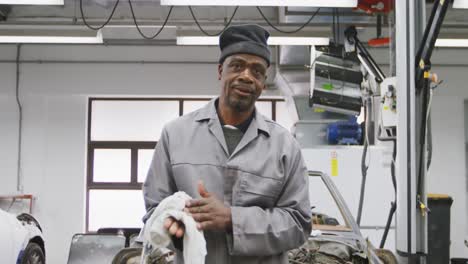 Afroamerikanischer-Männlicher-Automechaniker,-Der-Seine-Hände-Mit-Einem-Lappen-Reinigt
