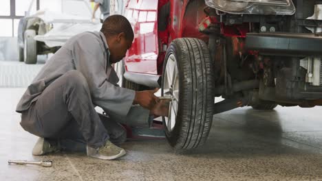 African-American-male-car-mechanic--screwing-a-wheel-to-a-car-with-a-wrench