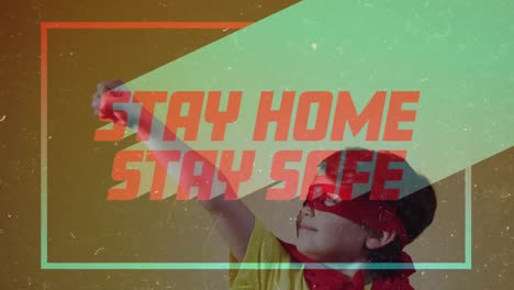 Animation-of-red-text-Stay-Home-Stay-Safe-in-colourful-frame-over-Caucasian-boy-wearing-a-cape
