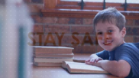 Animation-of-social-distancing-message-over-Caucasian-boy-reading-a-book