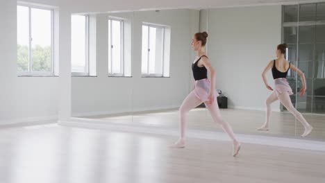 Caucasian-female-ballet-dancer-practicing-ballet-during-a-dance-class-in-a-bright-studio