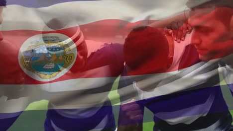 Animation-of-Costa-Rican-flag-waving-over-multi-ethnic-male-rugby-team