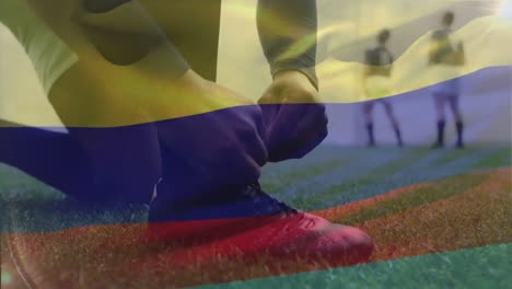 Animation-of-Colombian-flag-waving-over-mixed-race-male-rugby-player-tying-a-shoe