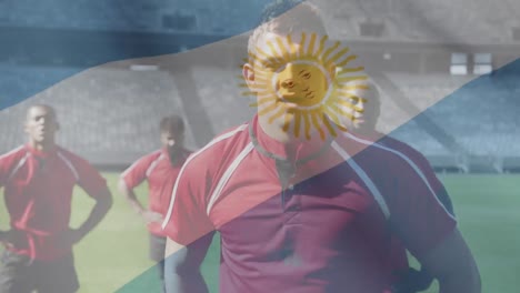 Animation-of-Argentinian-flag-waving-over-multi-ethnic-male-rugby-team-standing-on-a-pitch