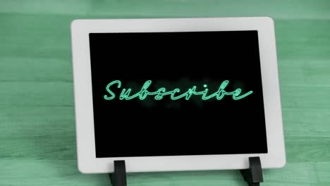 Animation-of-green-neon-style-word-Subscribe-flickering-on-screen-of-digital-tablet-