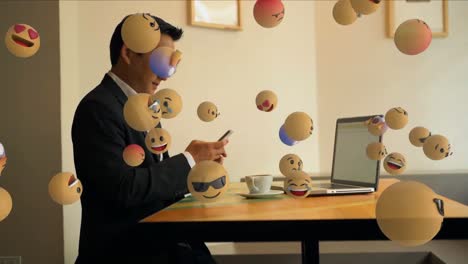 Animation-Eines-Gemischtrassigen-Mannes,-Der-Am-Schreibtisch-Sitzt-Und-Schwebende-3D-Emojis-Trägt