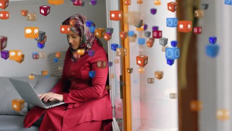 Face-emojis-and-digital-icons-moving-against-woman-in-hijab-using-laptop