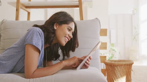 Schöne-Frau,-Die-Ein-Digitales-Tablet-Benutzt,-Während-Sie-Auf-Der-Couch-Liegt