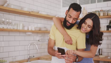 Happy-couple-looking-at-each-other-while-using-smartphone