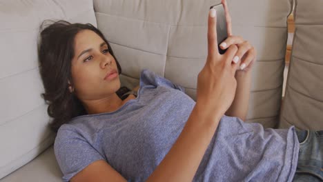 Schöne-Frau,-Die-Ihr-Smartphone-Benutzt,-Während-Sie-Auf-Der-Couch-Liegt