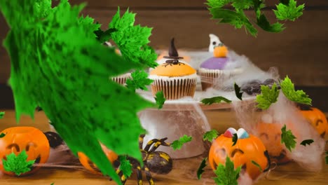 Digitales-Zusammengesetztes-Video-Von-Herbstblättern,-Die-Auf-Halloween-Cupcakes-Im-Hintergrund-Fallen