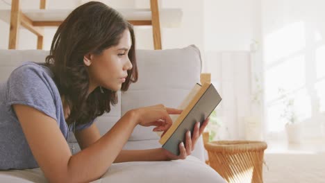 Schöne-Frau-Liest-Bücher,-Während-Sie-Auf-Der-Couch-Liegt