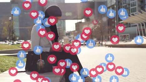 Social-media-emojis-against-woman-in-hijab-using-digital-tablet