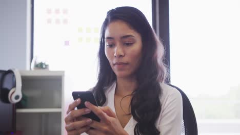 Professional-businesswoman-using-smartphone-while-sitting-on-her-desk-in-office-in-slow-motion