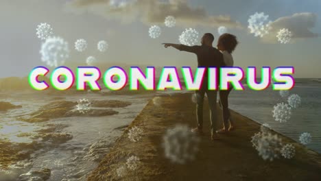Digital-composite-video-of-Covid-19-cells-moving-against-couple-watching-sea-shore-in-background