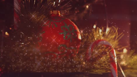 Digital-composite-video-of-silver-sparkles-moving-against-baubles-hanging-on-a-christmas-tree