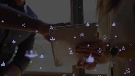Digital-composite-video-of-web-of-connections-with-icons-moving-against-people-using-a-digital-table