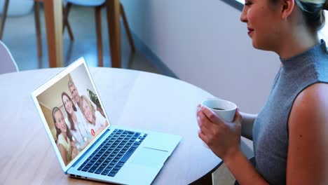 Kreative-Geschäftsfrau-Hält-Eine-Kaffeetasse-In-Der-Hand-Und-Führt-Einen-Video-Chat-Auf-Ihrem-Laptop