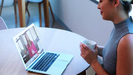 Mujer-De-Negocios-Creativa-Sosteniendo-Una-Taza-De-Café-Y-Teniendo-Una-Reunión-De-Video-En-Su-Computadora-Portátil