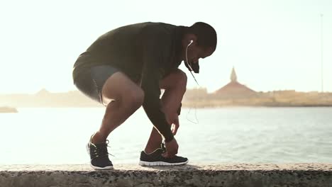 Man-tying-his-shoe-laces-while-running-on-the-promenade
