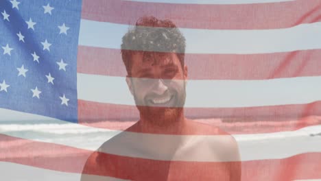 Animation-of-American-flag-waving-over-portrait-of-happy-Caucasian-man-on-beach-by-seaside