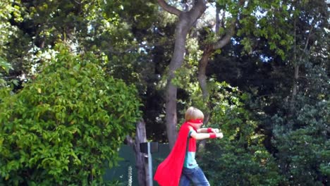 Wow-and-Pow-text-against-boy-in-superhero-costume-running-in-the-garden