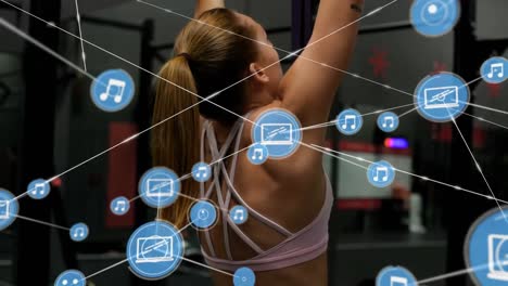 Network-of-connection-icons-against-woman-performing-pull-up-exercise-at-the-gym