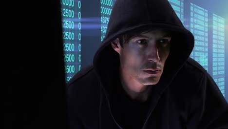Animation-of-male-hacker-wearing-hoodie,-using-laptop-over-multiple-screens